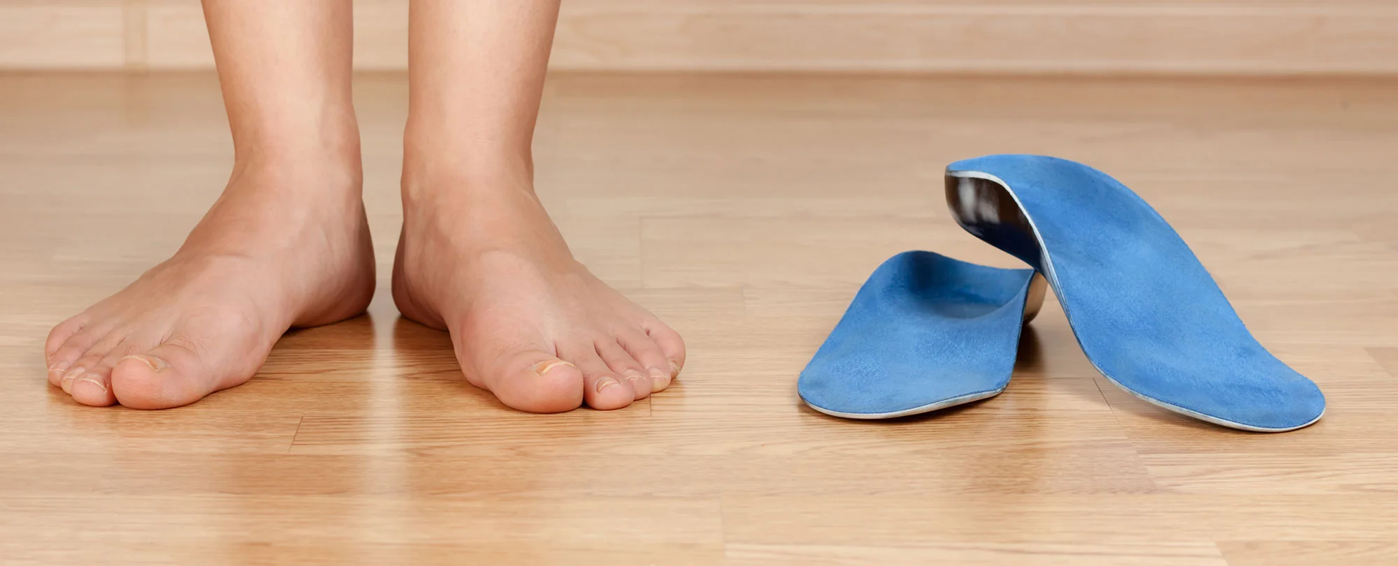Bare feet beside custom arch-support orthotics for plantar fasciitis